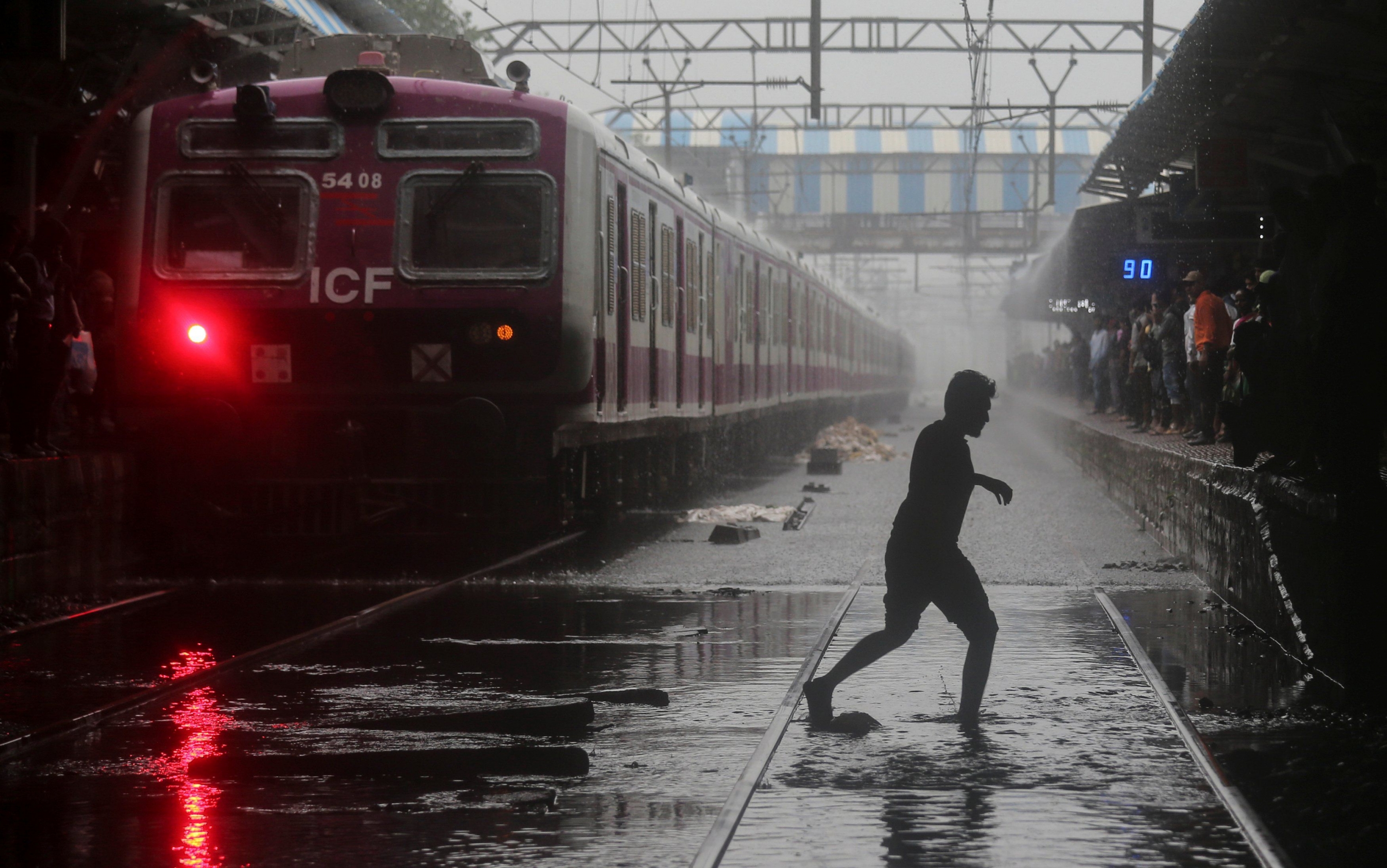 Un viajero cruza las vías del tren afectadas por las lluvias. (Foto: Reuters)