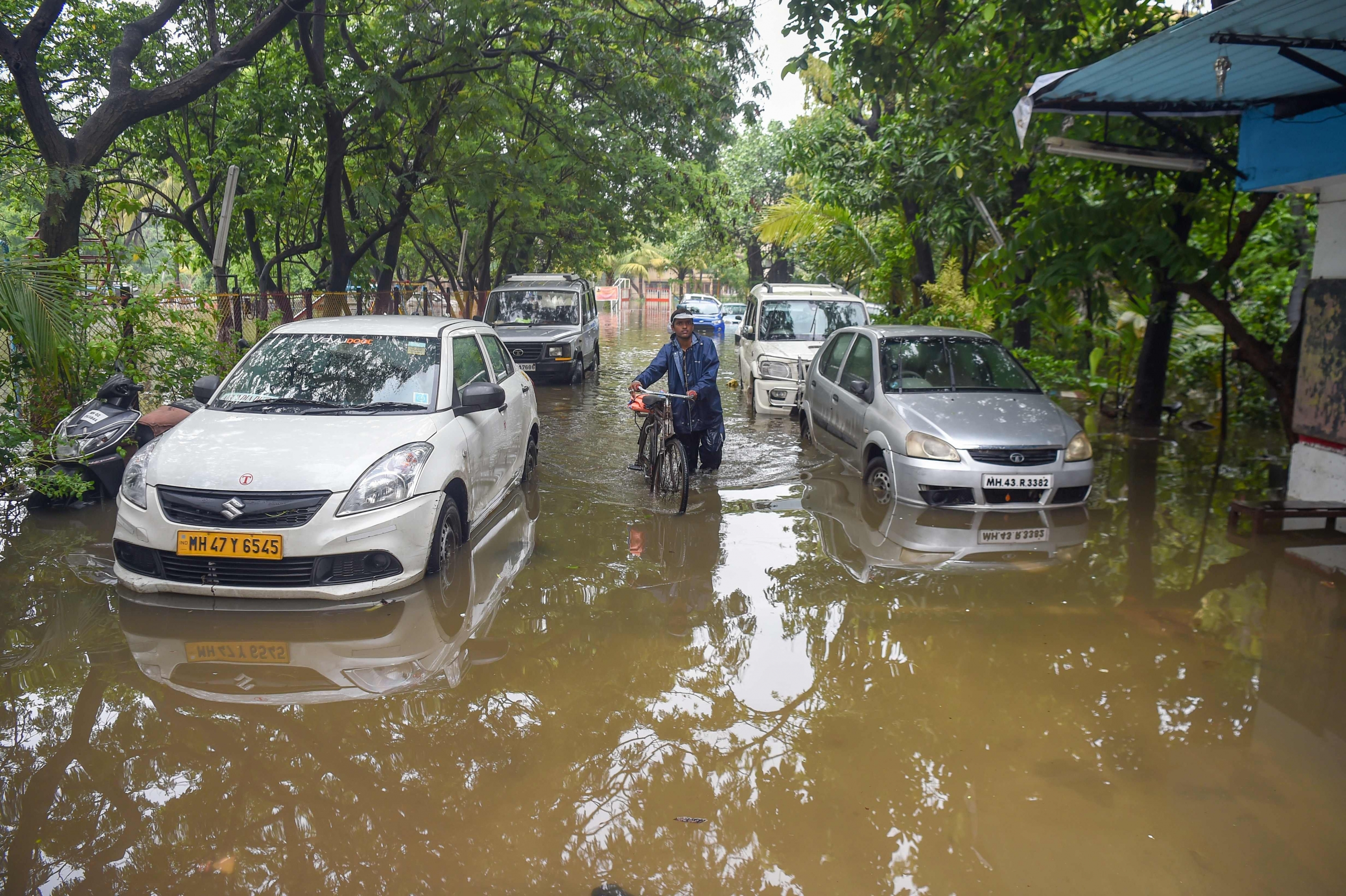 Un hombre de la India camina con una bicicleta a lo largo de una calle mojada en Mumbai. (Foto: Reuters)